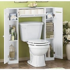 a white toilet sitting in a bathroom next to a shelf filled with towels and other items