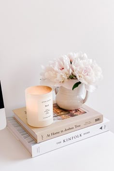 a white vase filled with flowers sitting on top of two books