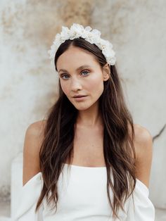 a woman with long hair wearing a white dress and a flower headband on her head