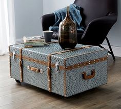 a blue suitcase sitting on top of a wooden floor next to a chair and coffee table