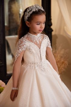 Make your little one feel like a princess in the Pentelei Couture 3611 Flower Girl Floor Length Dress in Blush. This stunning gown features an all over sheer crystal beaded bodice with a sheer nude deep V neckline and long sleeves, creating a delicate and ethereal look. The nude back is embellished with shimmering crystal beads and finished with crystal button accents for added sparkle. The voluminous glitter skirt with a train adds a touch of whimsy and drama, perfect for any special occasion. Baju Kahwin, Girls Pageant Dresses, Christening Dress, Beaded Bodice, Stunning Gowns