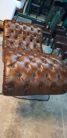 a brown leather chair sitting on top of a tile floor next to chairs and tables