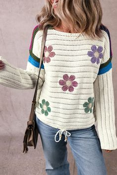 a woman wearing a white sweater with flowers on it