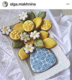 there is a plate with cookies decorated like flowers and lemons on it that are sitting on a lace doily