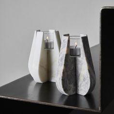 three marble vases sitting on top of a black shelf next to a cell phone