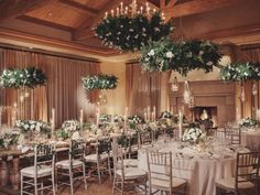 a dining room with tables and chairs covered in white flowers, greenery and candles