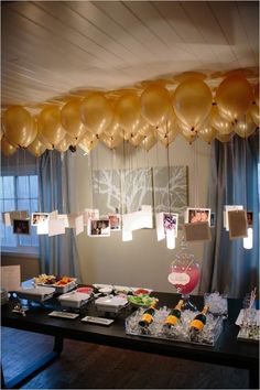 some balloons are hanging from the ceiling above a table with food and drinks on it