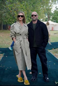 a man and woman standing next to each other on a blue carpet in the park