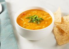 a white bowl filled with soup next to tortilla chips on a blue towel