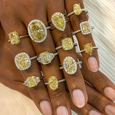 a woman's hand with five different rings on her fingers and four yellow diamonds in the middle