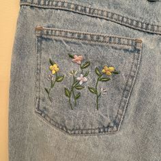 a pair of jeans with embroidered flowers on them