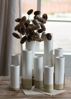 a bunch of white vases sitting on top of a wooden table