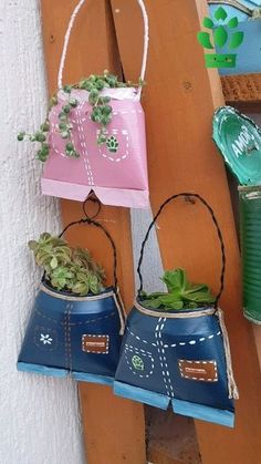 two blue and pink pots with plants in them hanging on a wooden wall next to a green planter