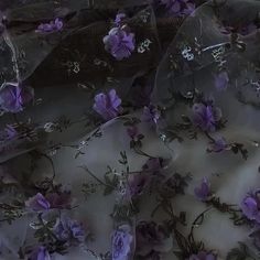 purple flowers and leaves are scattered on a white sheet with sheer, lacy netting over it