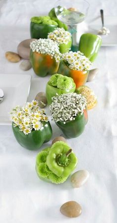 there are many green apples with flowers in them on the white table cloth and rocks