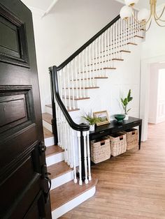 an entryway with stairs and baskets under the bannister in this home's foyer