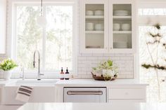 a kitchen with white cabinets and counter tops next to a dishwasher, sink and window