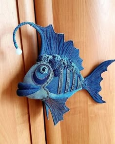 a blue fish made out of jeans hanging on a wooden door