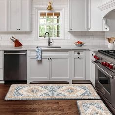 a kitchen with white cabinets and wood flooring next to a stove top oven, dishwasher and sink