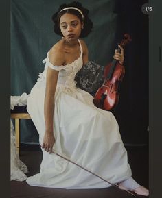 a woman in a white dress holding a violin