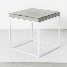 a white square table sitting on top of a cement floor