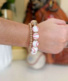 a close up of a person's arm wearing a bracelet with baseballs on it