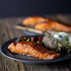 a plate with meat, potatoes and bread on it sitting on top of a wooden table