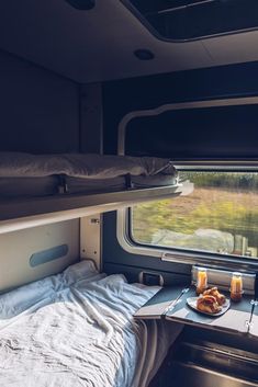 a bed in a small room next to a window with food on the table near by