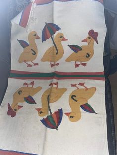 an old blanket with ducks and umbrellas on the front is sitting on a chair