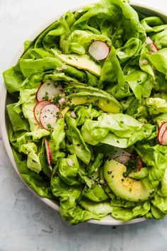 a white bowl filled with lettuce and radishes