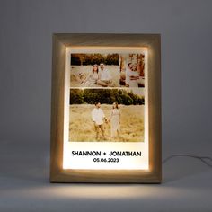 an illuminated photo frame with two people standing in a field and the light is turned on