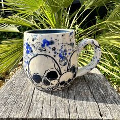 a blue and white coffee mug sitting on top of a wooden table next to plants