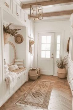 a hallway with white walls and wooden floors, rugs on the floor and potted plants