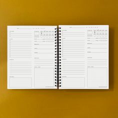 a spiral bound planner is open on a yellow surface