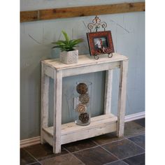 a small white table with a potted plant on top and an empty shelf below it