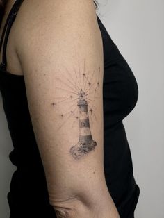 a woman's arm with a lighthouse tattoo on it