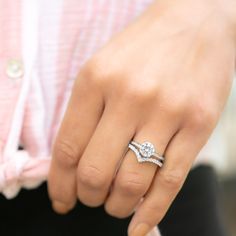 a woman's hand with a diamond ring on top of her finger and a pink shirt