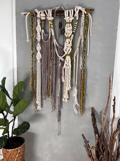 a wall hanging made out of macrame beads and rope with a potted plant next to it