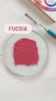 a white plate topped with red paint next to a painting brush and acrylic