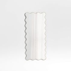 a white wall mirror with scalloped edges