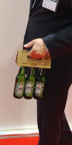 the man is holding three beer bottles in his hand