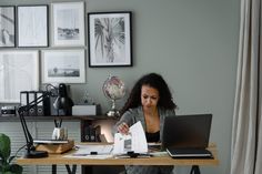 a woman sitting at a desk in front of a laptop computer with papers on it