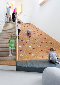 two children are climbing up the stairs in an indoor play area that is decorated with colorful rocks