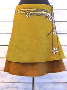 a yellow skirt with white flowers on the side and black top, sitting on a wooden stand