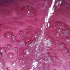 water is pouring into a purple bowl filled with liquid