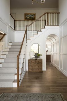 a staircase leading to the second floor with white walls and wood floors, along with a rug on the floor