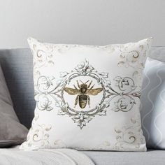 a white and gold pillow with a bee in the center on top of a couch