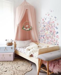 a pink canopy bed sitting in a bedroom next to two suitcases and a rug