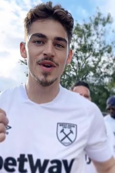 a man in a white shirt is giving the thumbs up sign with his right hand