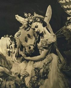 an old photo of two women dressed as fairy tale characters, one holding the head of a dog